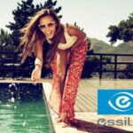 woman wearing trendy sunglasses, laughing, playing with water at pool