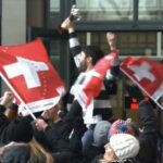 People at railstation bear supporter of Swiss Olympic Team on shoulders